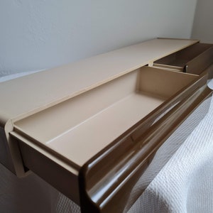 Puede incluir: Una estanter&iacute;a de pared de pl&aacute;stico beige con dos cajones extra&iacute;bles. Los cajones tienen un borde marr&oacute;n y est&aacute;n abiertos, revelando el interior vac&iacute;o.
