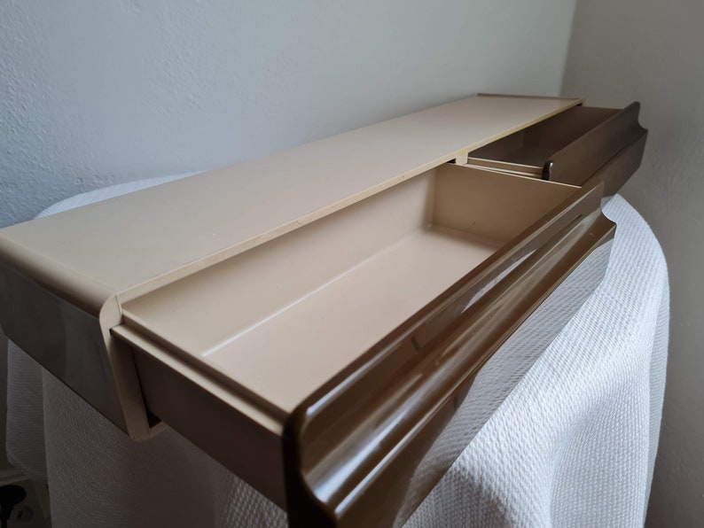 Puede incluir: Una estanter&iacute;a de pared de pl&aacute;stico beige con dos cajones extra&iacute;bles. Los cajones tienen un borde marr&oacute;n y est&aacute;n abiertos, revelando el interior vac&iacute;o.