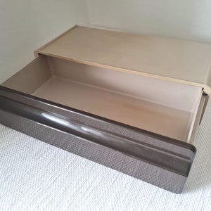 Puede incluir: Un caj&oacute;n de pl&aacute;stico beige con un caj&oacute;n de pl&aacute;stico marr&oacute;n extra&iacute;do. El caj&oacute;n est&aacute; vac&iacute;o.