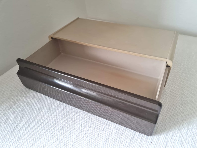 Puede incluir: Un caj&oacute;n de pl&aacute;stico beige con un caj&oacute;n de pl&aacute;stico marr&oacute;n extra&iacute;do. El caj&oacute;n est&aacute; vac&iacute;o.