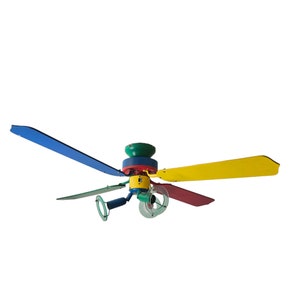 May include: A multi-coloured ceiling fan with blades in blue, yellow, red, and green. The motor housing is a combination of green, blue, red, and yellow. The fan has a unique, playful design, suitable for a child's room or a vibrant space.