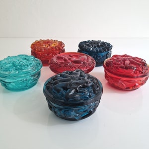 May include: Six small glass trinket boxes with intricate designs. The boxes are in various colors, including red, blue, and green.