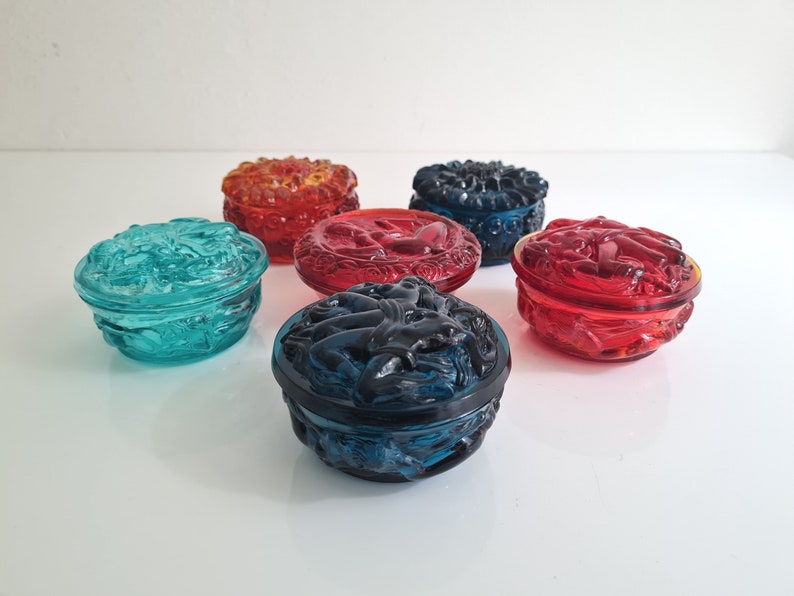 May include: Six small glass trinket boxes with intricate designs. The boxes are in various colors, including red, blue, and green.