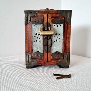 May include: A small wooden jewelry box with a carved white jade front and brass accents. The box has a lock and key.
