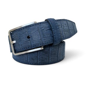 Può includere: Una cintura blu navy con un motivo testurizzato in pelle di coccodrillo e finitura opaca. La cintura presenta una fibbia rettangolare in metallo color argento con un ardiglione singolo e un passante in pelle blu navy per fissare l'estremità.