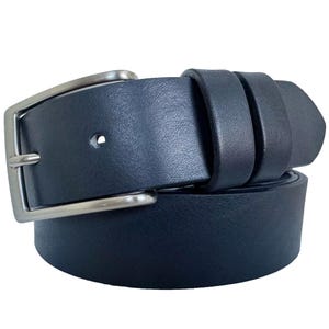 Puede incluir: Un cinturón de cuero azul marino con una hebilla plateada. El cinturón está abrochado y asegurado. Un accesorio clásico para pantalones y vaqueros. El cinturón es de cuero.
