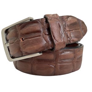Op de afbeelding: Een bruine leren riem met een krokodilpatroon en een zilveren gesp.