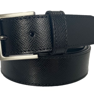 Puede incluir: Un cinturón de cuero negro con una hebilla plateada. El cinturón tiene una superficie texturizada y está enrollado.