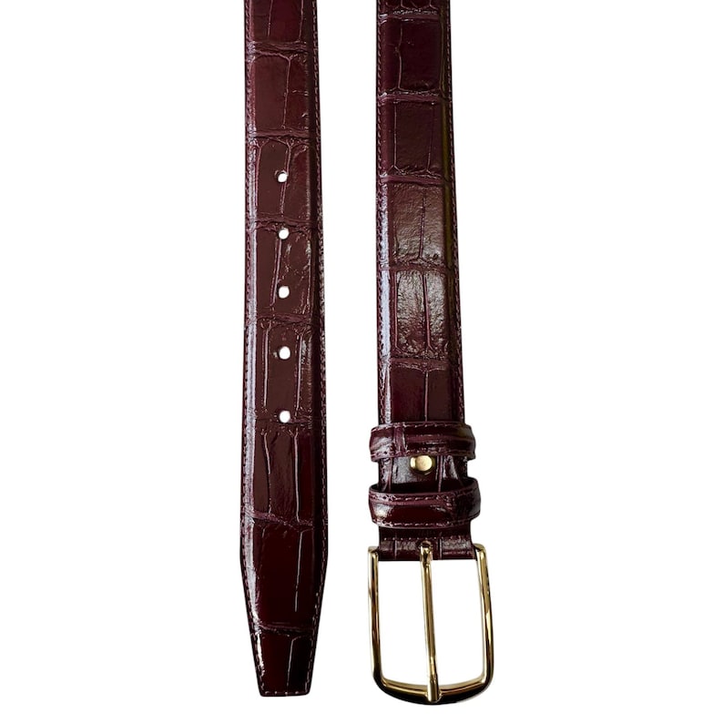 May include: A burgundy leather belt with a crocodile pattern and a gold buckle.