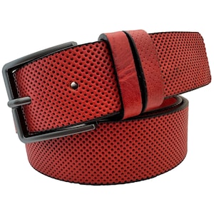 Op de afbeelding: Een rode leren riem met een zwarte metalen gesp. De riem heeft een geperforeerd ontwerp.