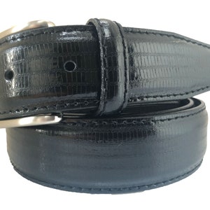 May include: A black leather belt with a silver buckle. The belt has a textured, alligator-like pattern.
