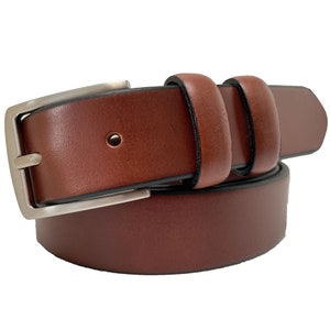 Peut inclure: Une ceinture en cuir marron avec une boucle argentée. La ceinture est pliée en deux et la boucle est visible.