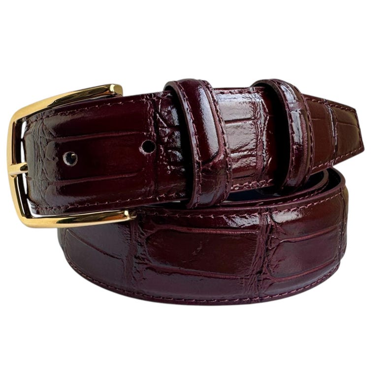 May include: A burgundy alligator leather belt with a gold buckle.