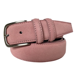 May include: A dusty rose suede belt with a silver-tone buckle. The belt has two loops and a single belt hole. The belt is rolled up, showing the texture of the suede material. The buckle is a simple, rectangular design.
