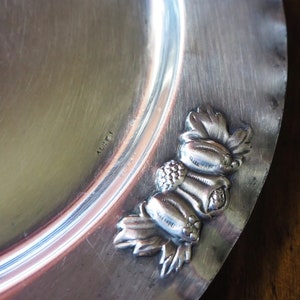 May include: A silver serving dish with a decorative border of grapes and leaves. The dish is marked "ALFI" on the bottom.