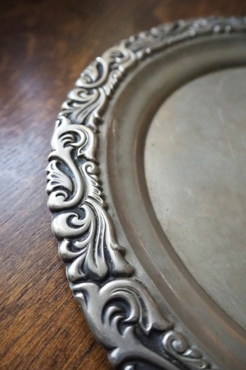 May include: A silver oval serving tray with an ornate, embossed, scroll-like design around the edge.