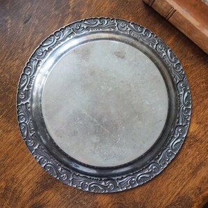 May include: A silver serving tray with an ornate, embossed design around the edge.