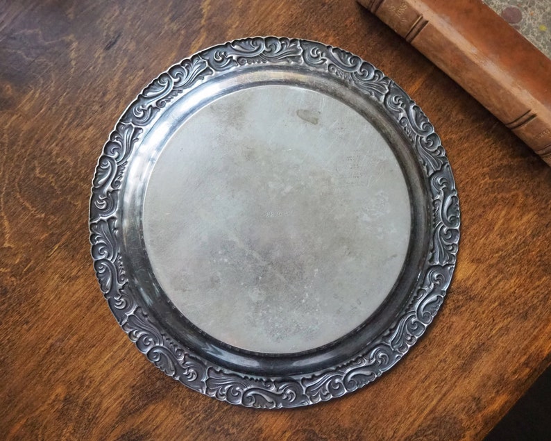 May include: A silver serving tray with an ornate, embossed design around the edge.