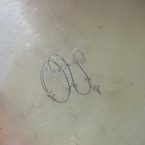 May include: Close-up of a silver surface with an engraved monogram of the letters "M" and "S" in a decorative script.