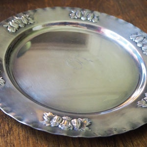 May include: A silver serving tray with a decorative border of embossed grapes and leaves.