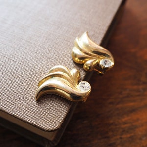 May include: A pair of gold-tone earrings with a leaf design and clear rhinestones.