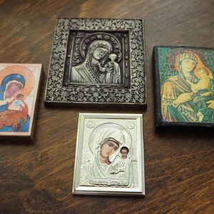 Pu&ograve; includere: Quattro icone religiose incorniciate con immagini della Vergine Maria e del bambino Ges&ugrave;. Le icone sono in diversi stili e colori, tra cui argento, oro e blu.