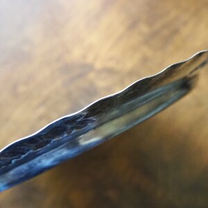 May include: A silver serving tray with a scalloped edge and a decorative embossed design.