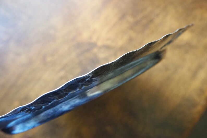 May include: A silver serving tray with a scalloped edge and a decorative embossed design.