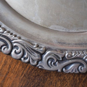 May include: Silver serving platter with a decorative, ornate, scalloped edge.