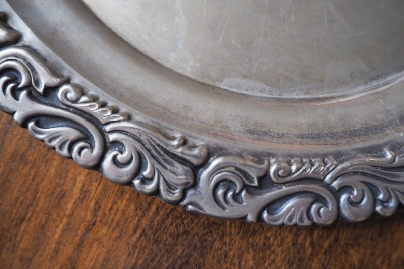 May include: Silver serving platter with a decorative, ornate, scalloped edge.