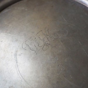 May include: A silver tray with a decorative engraved design. The design features a stylized floral motif and the initials "W.L."