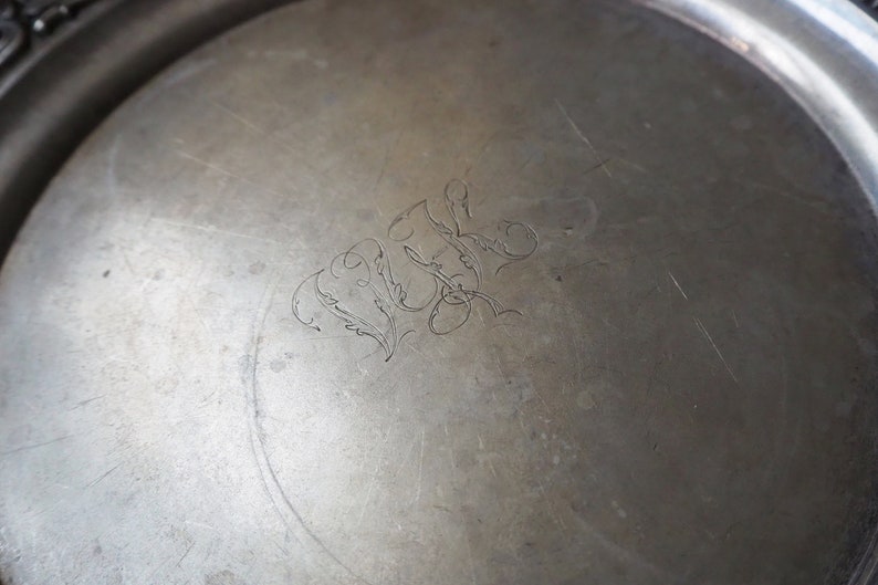 May include: A silver tray with a decorative engraved design. The design features a stylized floral motif and the initials "W.L."