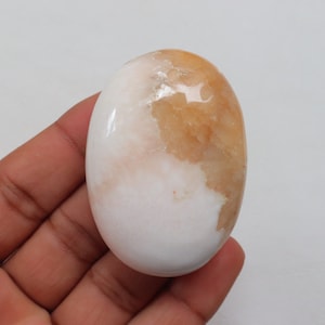 Op de afbeelding: Een gladde, ovale, witte en oranje edelsteen met een gepolijste afwerking.