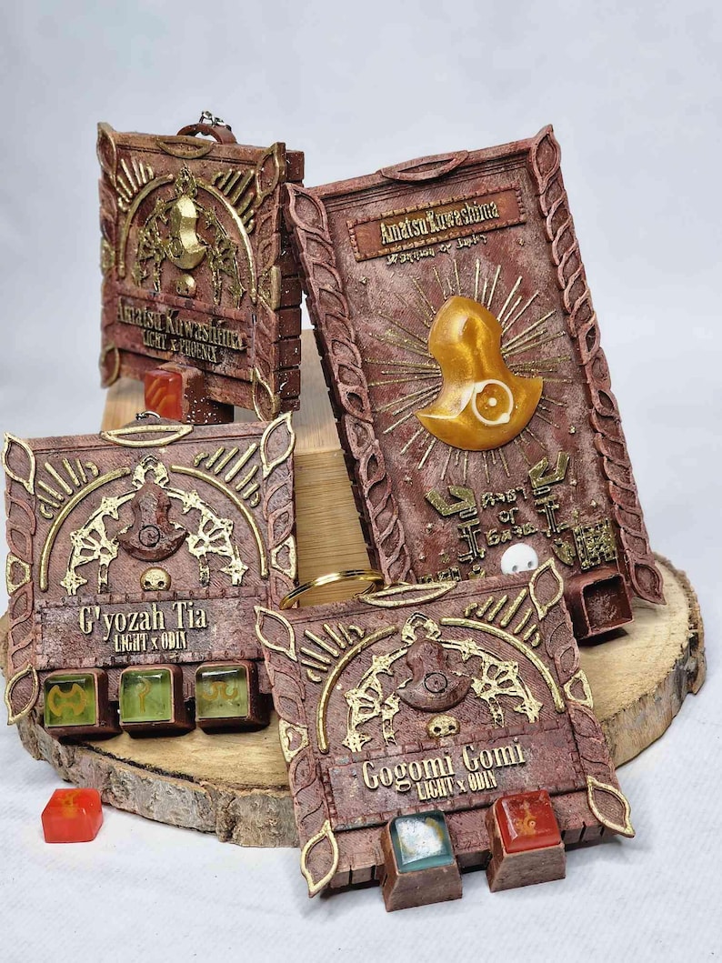 May include: Four intricately designed, rectangular, brown and gold decorative boxes with text and symbols. Each box has a different design and text, including "Amatsu Kuwashima", "C'yozah Tia", and "Gogomi Gomi". Some boxes have small, colorful cubes.