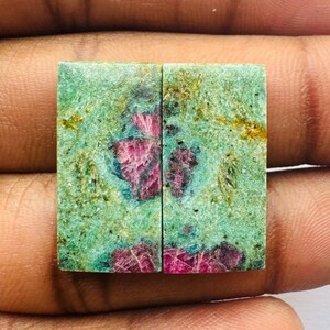 Può includere: Due cabochon rettangolari di rubino verde e rosa con taglio grezzo. Le pietre sono disposte in fila e misurano circa 2,5 cm di lunghezza.
