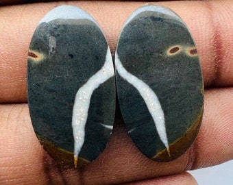 May include: Pair of oval-shaped cabochon stones with a black, white, and brown pattern. The stones have a natural, organic look.