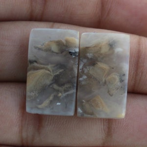 May include: Two rectangular, translucent, white agate cabochons with brown and gray patterns. The cabochons are smooth and polished.