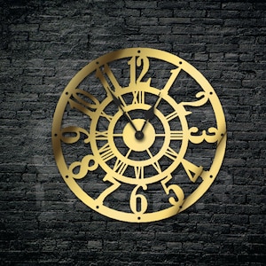 Può includere: Un orologio in metallo dorato con numeri romani e numeri arabi attorno al bordo. Il quadrante dell'orologio ha un design decorativo con una lancetta dell'orologio nera.