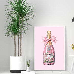 May include: A pink champagne bottle with a gold top and a pink bow. The bottle is decorated with pink flowers and has a pink background.