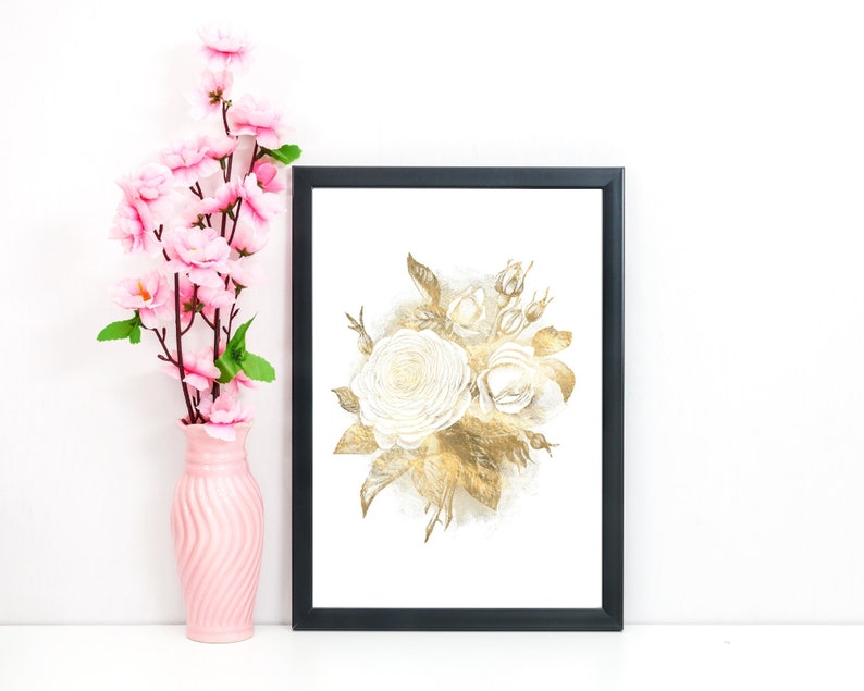 May include: A framed art print featuring a watercolor illustration of white and gold roses. The artwork is in a black frame and is displayed next to a pink vase with pink flowers. The overall aesthetic is elegant and floral.