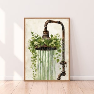 Op de afbeelding: Een roestige metalen douchekop met groene wijnstokken en witte bloemen die eromheen groeien. Water druppelt uit de douchekop.