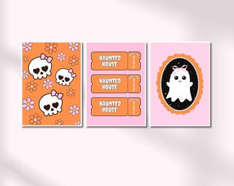 May include: Three Halloween-themed art prints. One features skulls with bows on an orange background with flowers. Another shows orange "Haunted House" tickets. The third print has a ghost in an oval frame with a pink background.
