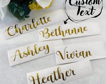 May include: White rectangular name tags with gold cursive lettering. Names include Charlotte, Bethanne, Ashley, Vivian, and Heather. The words "Custom Text" are in a black circle.