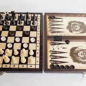 Puede incluir: Un juego de viaje de madera con un tablero de ajedrez en un lado y un tablero de backgammon en el otro. El tablero de ajedrez tiene casillas blancas y negras y el tablero de backgammon tiene un diseño de león.