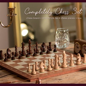 Puede incluir: Un juego de ajedrez de madera con piezas marrones y blancas sobre un tablero de madera. El juego incluye un reloj de ajedrez y el texto "Completely Chess Set chess board + STAUNTON No 4 chess pieces + box".