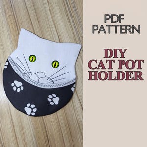 May include: A PDF pattern for a DIY cat pot holder. The image shows a white cat face with green eyes and black whiskers, featuring a black pocket section decorated with white paw prints. The text reads PDF PATTERN DIY CAT POT HOLDER.