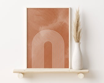 May include: Framed abstract art print featuring a white arched design on a terracotta background. The artwork is displayed on a light wood shelf, next to a white vase with dried pampas grass.