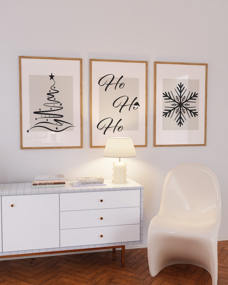 May include: Three framed prints with a Christmas theme. The left print features a stylized black Christmas tree with stars. The middle print has the text "Ho Ho Ho" in black cursive. The right print features a black snowflake.