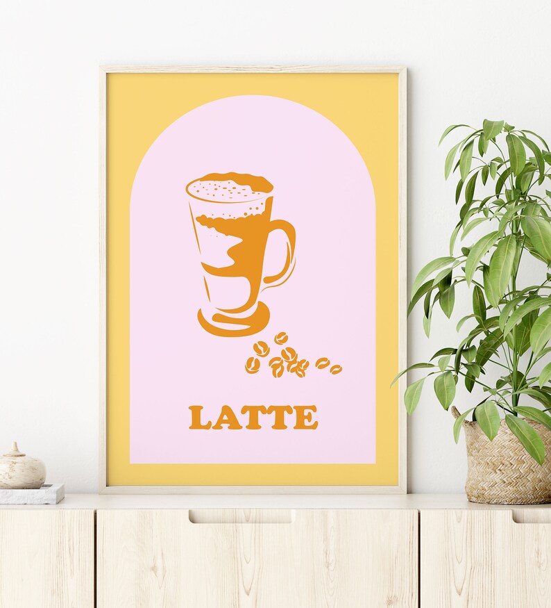 May include: A yellow and pink poster with a graphic of a latte in a glass with coffee beans scattered around it. The text "LATTE" is printed in orange below the graphic.