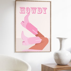 Pu&ograve; includere: Un poster rosa e bianco con la parola "HOWDY" in lettere rosa con contorno bianco. Il poster presenta un paio di stivali da cowboy rosa con una gamba color bronzo che sporge dalla parte superiore degli stivali.